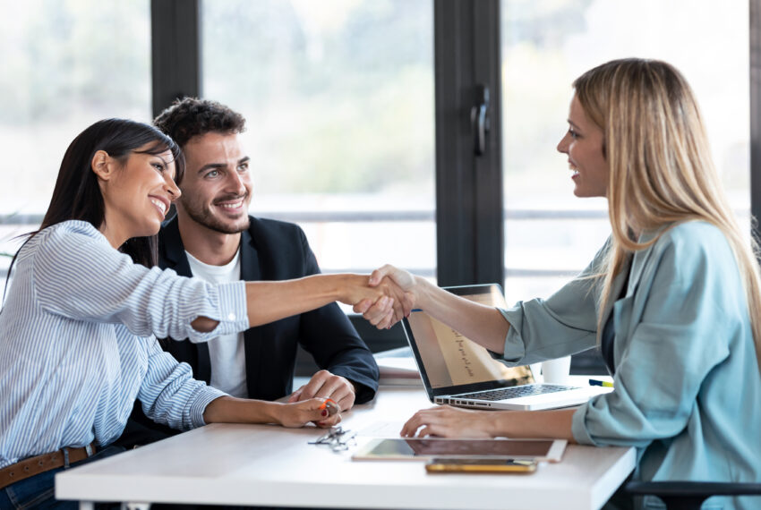 Shot,Of,Attractive,Real-estate,Agent,Shaking,Hands,With,Young,Couple